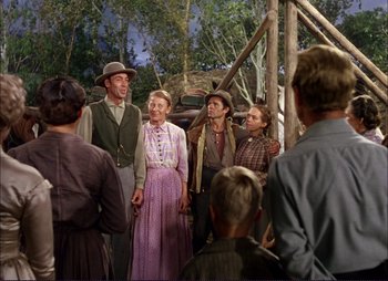 Movie still from “Shane” (1953), directed by George Stevens – A group of men and women standing in front of a group of people; Wide shot, Over the shoulder angle