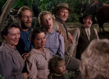 Movie still from “Shane” (1953), directed by George Stevens – A group of people standing next to each other in a field; Medium shot, Low angle