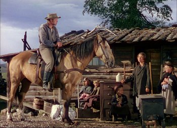 Movie still from “Shane” (1953), directed by George Stevens – A man on a horse in front of a log cabin; Wide shot, Low angle
