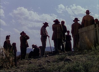 Movie still from “Shane” (1953), directed by George Stevens – A group of men standing on top of a grass covered hill; Extreme Wide shot, Low angle