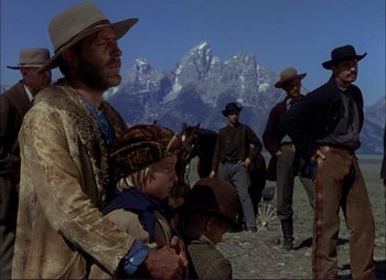 Movie still from “Shane” (1953), directed by George Stevens – A group of men standing next to each other on top of a hill; Medium shot, Over the shoulder angle