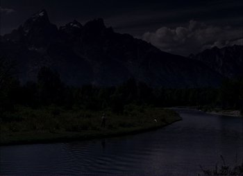 Movie still from “Shane” (1953), directed by George Stevens – A man standing in a river at night with mountains in the background; Extreme Wide shot, High angle