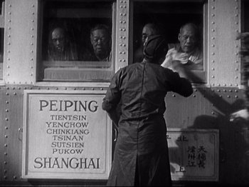 Movie still from “Shanghai Express” (1932), directed by Josef von Sternberg – An old black and white photo of a man looking out a window; Medium shot, High angle