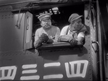 Movie still from “Shanghai Express” (1932), directed by Josef von Sternberg – A black and white photo of two men sitting in a train car; Medium shot, Low angle