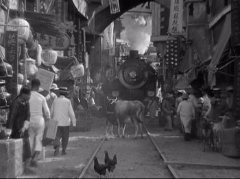 Movie still from “Shanghai Express” (1932), directed by Josef von Sternberg – A black and white photo of a city street with people and animals; Extreme Wide shot, High angle