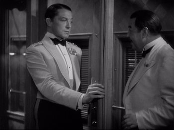 Movie still from “Shanghai Express” (1932), directed by Josef von Sternberg – A man in a tuxedo and a man in a suit and bow tie; Medium shot, Over the shoulder angle