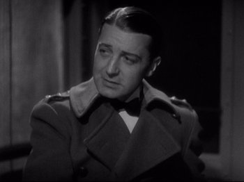 Movie still from “Shanghai Express” (1932), directed by Josef von Sternberg – A man wearing a trench coat and a bow tie; Close Up shot, High angle