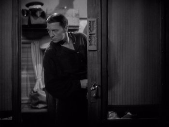 Movie still from “Shanghai Express” (1932), directed by Josef von Sternberg – A black and white photo of a man standing in front of an open door; Medium shot, High angle