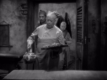 Movie still from “Shanghai Express” (1932), directed by Josef von Sternberg – An older man holding a tray of food in front of two other men; Medium shot, High angle