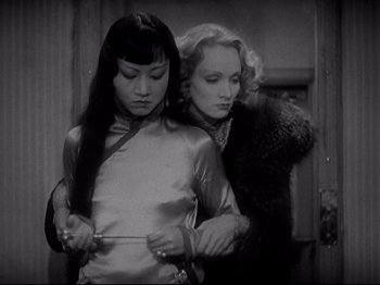 Movie still from “Shanghai Express” (1932), directed by Josef von Sternberg – Two women are holding a pair of shears in their hands; Medium shot, Over the shoulder angle