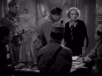 Movie still from “Shanghai Express” (1932), directed by Josef von Sternberg – A group of people standing around a table; Medium shot, Over the shoulder angle