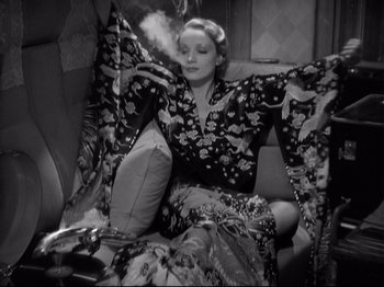Movie still from “Shanghai Express” (1932), directed by Josef von Sternberg – A black and white photo of a woman smoking a cigarette; Medium shot, High angle