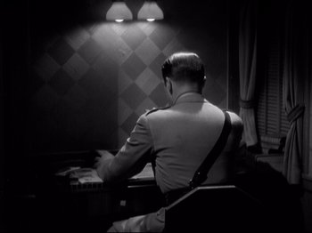 Movie still from “Shanghai Express” (1932), directed by Josef von Sternberg – A man sitting at a desk in front of a computer; Medium shot, High angle