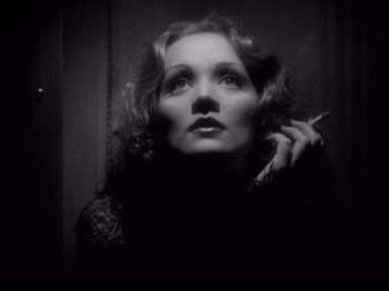 Movie still from “Shanghai Express” (1932), directed by Josef von Sternberg – A black and white photo of a woman smoking a cigarette; Close Up shot, Low angle