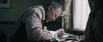 Movie still from “1922” (2017), directed by Zak Hilditch – An older man writing on a piece of paper; Close Up shot, Low angle