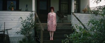 Movie still from “1922” (2017), directed by Zak Hilditch – A woman standing on the steps of a house wearing a hat; Wide shot, Low angle