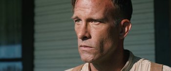 Movie still from “1922” (2017), directed by Zak Hilditch – A man's face in front of a building; Close Up shot, Low angle