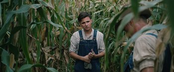 Movie still from “1922” (2017), directed by Zak Hilditch – A man in overalls standing in a corn field; Medium shot, Low angle