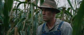 Movie still from “1922” (2017), directed by Zak Hilditch – A man wearing a hat standing next to a field of corn; Close Up shot, Low angle