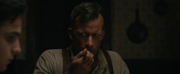 Movie still from “1922” (2017), directed by Zak Hilditch – A man in a brown shirt is eating a sandwich; Close Up shot, Over the shoulder angle