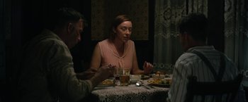 Movie still from “1922” (2017), directed by Zak Hilditch – A woman sitting at a table with two men; Medium shot, Over the shoulder angle