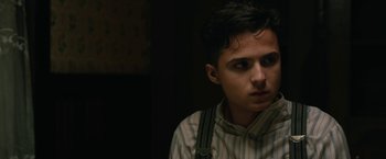 Movie still from “1922” (2017), directed by Zak Hilditch – A young man in a striped shirt is looking into the distance; Close Up shot, Over the shoulder angle