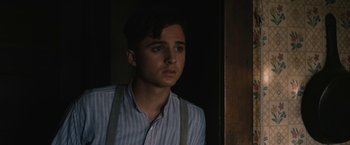 Movie still from “1922” (2017), directed by Zak Hilditch – A young man wearing suspenders looking out of a window; Close Up shot, Over the shoulder angle