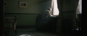 Movie still from “1922” (2017), directed by Zak Hilditch – An old man sitting in a chair in front of a window; Wide shot, High angle