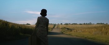 Movie still from “1922” (2017), directed by Zak Hilditch – A woman is walking down a road with a suitcase; Wide shot, Low angle
