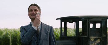 Movie still from “1922” (2017), directed by Zak Hilditch – A man talking on a cell phone while standing in front of a tractor; Close Up shot, Over the shoulder angle