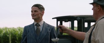 Movie still from “1922” (2017), directed by Zak Hilditch – A man in a suit and tie holding a cup; Medium shot, Over the shoulder angle