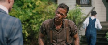 Movie still from “1922” (2017), directed by Zak Hilditch – A person wearing suspenders near a tree; Close Up shot, Over the shoulder angle