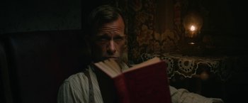 Movie still from “1922” (2017), directed by Zak Hilditch – A man sitting in front of an open book; Close Up shot, High angle