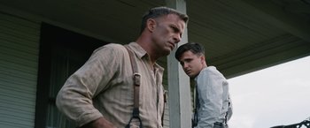 Movie still from “1922” (2017), directed by Zak Hilditch – Two men standing next to each other on a porch; Medium shot, Low angle