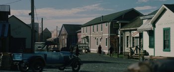 Movie still from “1922” (2017), directed by Zak Hilditch – A street scene with a horse drawn carriage and people walking down the street; Extreme Wide shot, Over the shoulder angle