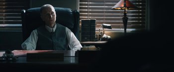 Movie still from “1922” (2017), directed by Zak Hilditch – A man sitting at a desk in front of a lamp; Medium shot, Over the shoulder angle