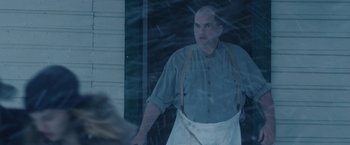 Movie still from “1922” (2017), directed by Zak Hilditch – A man wearing an apron standing in front of a window; Medium shot, Over the shoulder angle