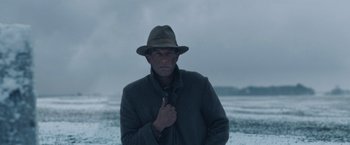 Movie still from “1922” (2017), directed by Zak Hilditch – A man wearing a hat standing on a beach; Medium shot, Low angle