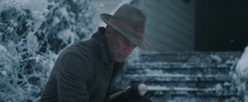 Movie still from “1922” (2017), directed by Zak Hilditch – A man wearing a hat and holding a cell phone; Close Up shot, Low angle