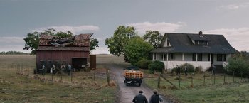 Movie still from “1922” (2017), directed by Zak Hilditch – Two men are walking down a dirt road with an old truck; Extreme Wide shot, High angle