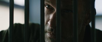 Movie still from “1922” (2017), directed by Zak Hilditch – A person behind a metal fence; Extreme Close Up shot, Over the shoulder angle