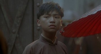 Movie still from “Shanghai Triad” (1995), directed by Yimou Zhang – A young man with a red umbrella in the background; Close Up shot, Over the shoulder angle