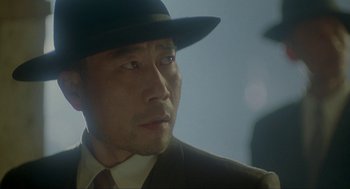 Movie still from “Shanghai Triad” (1995), directed by Yimou Zhang – A person wearing a suit and a hat; Close Up shot, Low angle