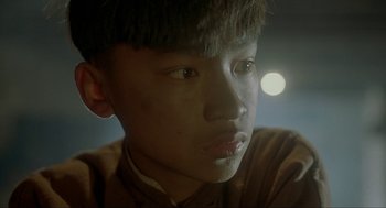 Movie still from “Shanghai Triad” (1995), directed by Yimou Zhang – A young man with a piercing is looking at the camera; Close Up shot, Low angle