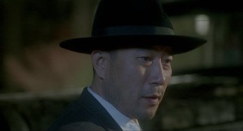 Movie still from “Shanghai Triad” (1995), directed by Yimou Zhang – A person wearing a suit and a hat; Close Up shot, Low angle
