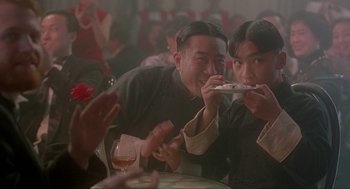 Movie still from “Shanghai Triad” (1995), directed by Yimou Zhang – A man and a woman eating food at a table; Medium shot, Over the shoulder angle