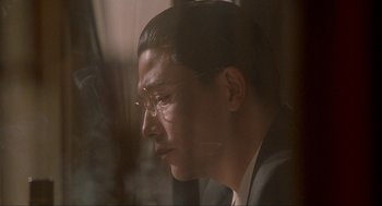 Movie still from “Shanghai Triad” (1995), directed by Yimou Zhang – A person wearing a suit and glasses; Close Up shot, Low angle