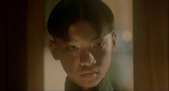 Movie still from “Shanghai Triad” (1995), directed by Yimou Zhang – A young man with a short hair cut looks into the camera; Close Up shot, Low angle