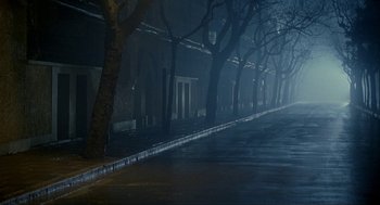Movie still from “Shanghai Triad” (1995), directed by Yimou Zhang – A dark street with trees in the background; Extreme Wide shot, High angle
