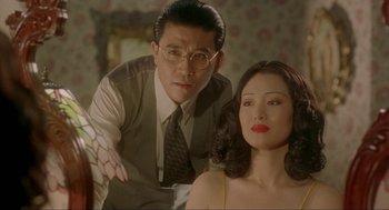 Movie still from “Shanghai Triad” (1995), directed by Yimou Zhang – A man and a woman sitting next to each other in a room; Close Up shot, Over the shoulder angle